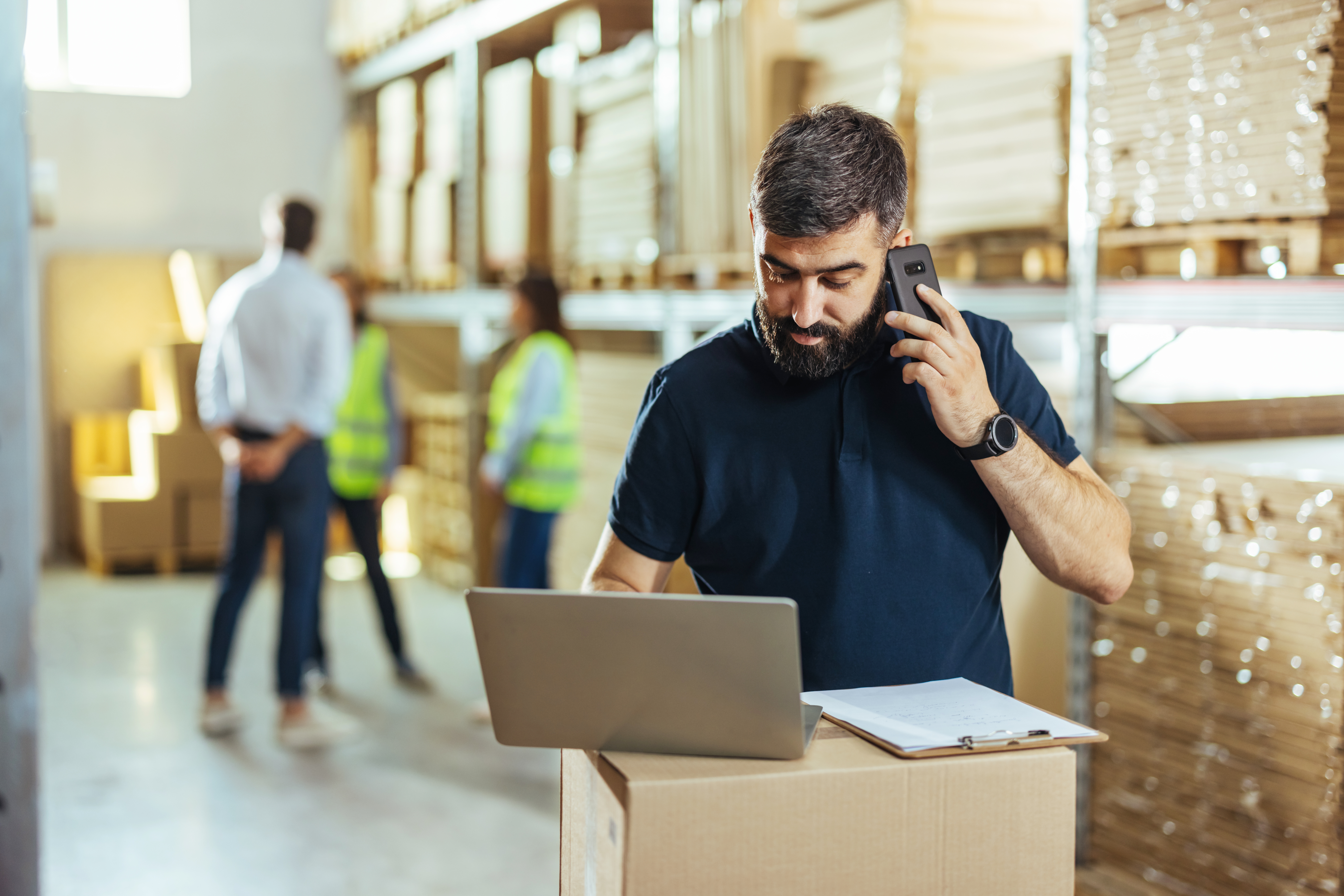 Worker on the phone in a warehouse with laptop in front of him